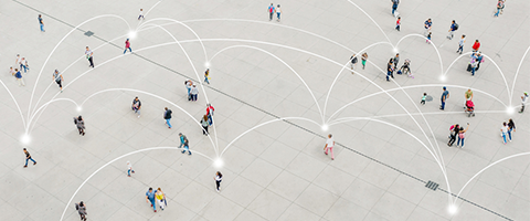An aerial view of a large public plaza filled with people walking, connected by glowing white arc lines radiating between them against a gray concrete surface, suggesting a network connectivity theme