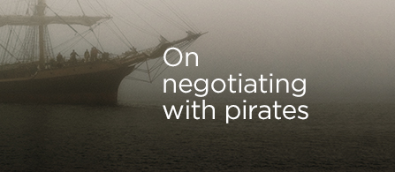 Promotional graphic featuring a historic sailing ship emerging from dense fog over dark water, with the headline "On negotiating with pirates."
