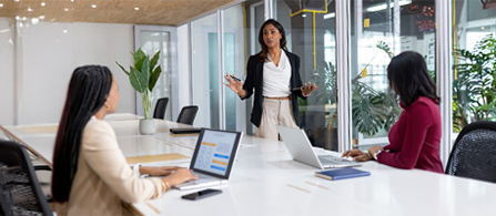 Team members gather around a conference table as a presenter leads a workplace discussion. 