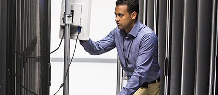 An individual in professional attire works on a standing monitor. 