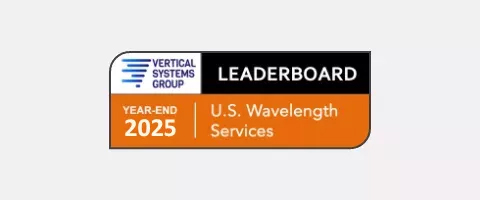 Badge graphic with white and orange panels. At the top, the 'VERTICAL SYSTEMS GROUP' logo with a blue striped icon sits beside a black bar reading 'LEADERBOARD.' Below, orange and white text reads 'YEAR-END 2025' and 'U.S. Wavelength Services.'