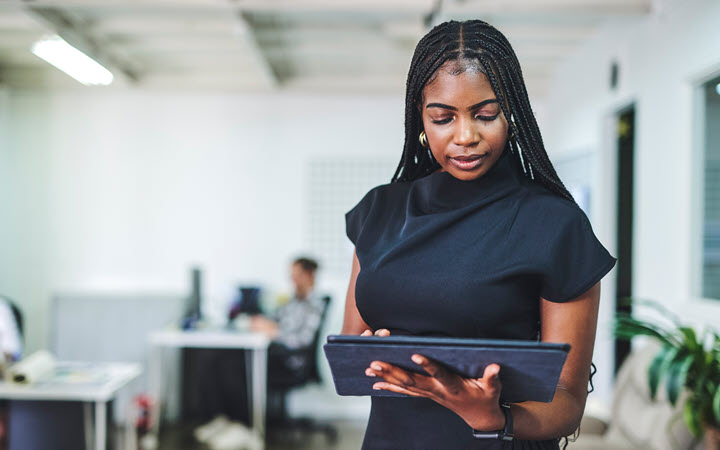 A woman in an office, standing, using tablet computer.