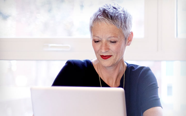 A woman working on a laptop and smiling