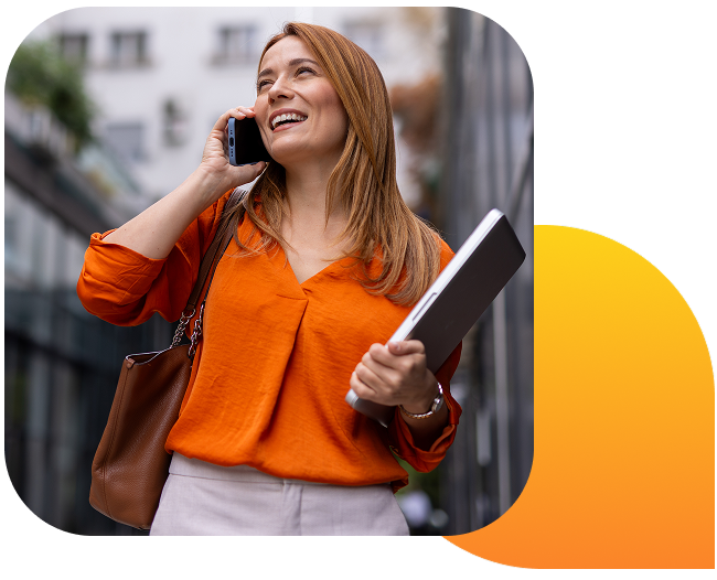 A happy woman talking on her cell phone while walking down the street.