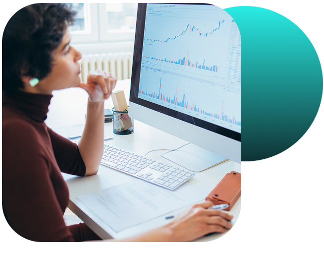 A woman evaluating data on a desktop computer in an office. 
