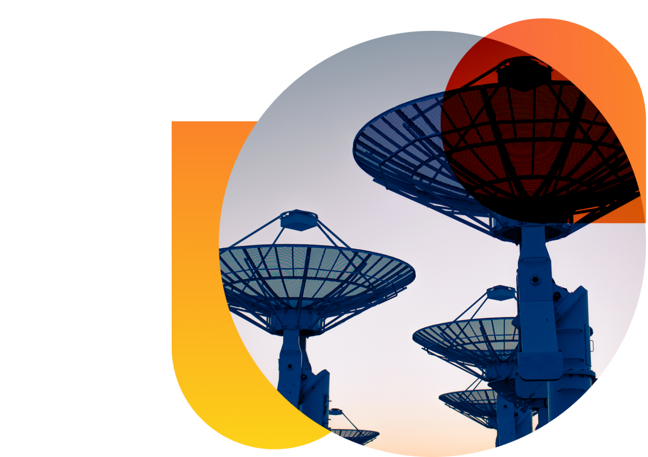 A field of satellite dishes at sunset.